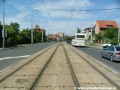 Přímý úsek tramvajové tratě zakryté zádlažbovými panely ve středu Bělohorské ulice.