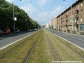 Zatravněný přímý úsek tramvajové tratě na zvýšeném tělese ve středu Černokostelecké ulice.