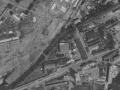 Areál Rustonky na leteckém snímku již nesousedí s vltavským říčním ramenem, které bylo zcela zasypáno, na nádvoří areálu vidíme zaparkované autobusy, pro než se Rustonka stala Ústředními dílnami. | 1975
