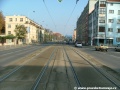 Středem Plzeňské ulice na zvýšeném tělese pokračuje tramvajová trať v klesání